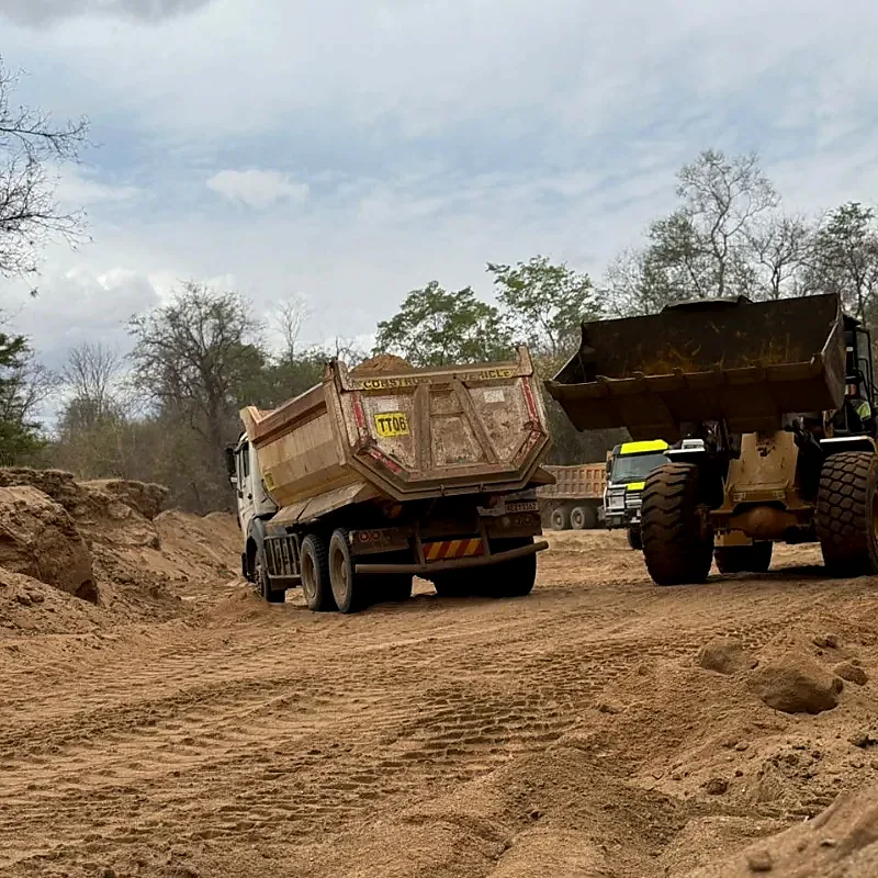 Wheel loader and tipper truck working beside sand stockpiles
