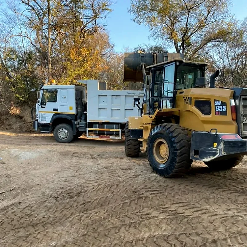 Yellow wheel loader alongside a material haulage truck